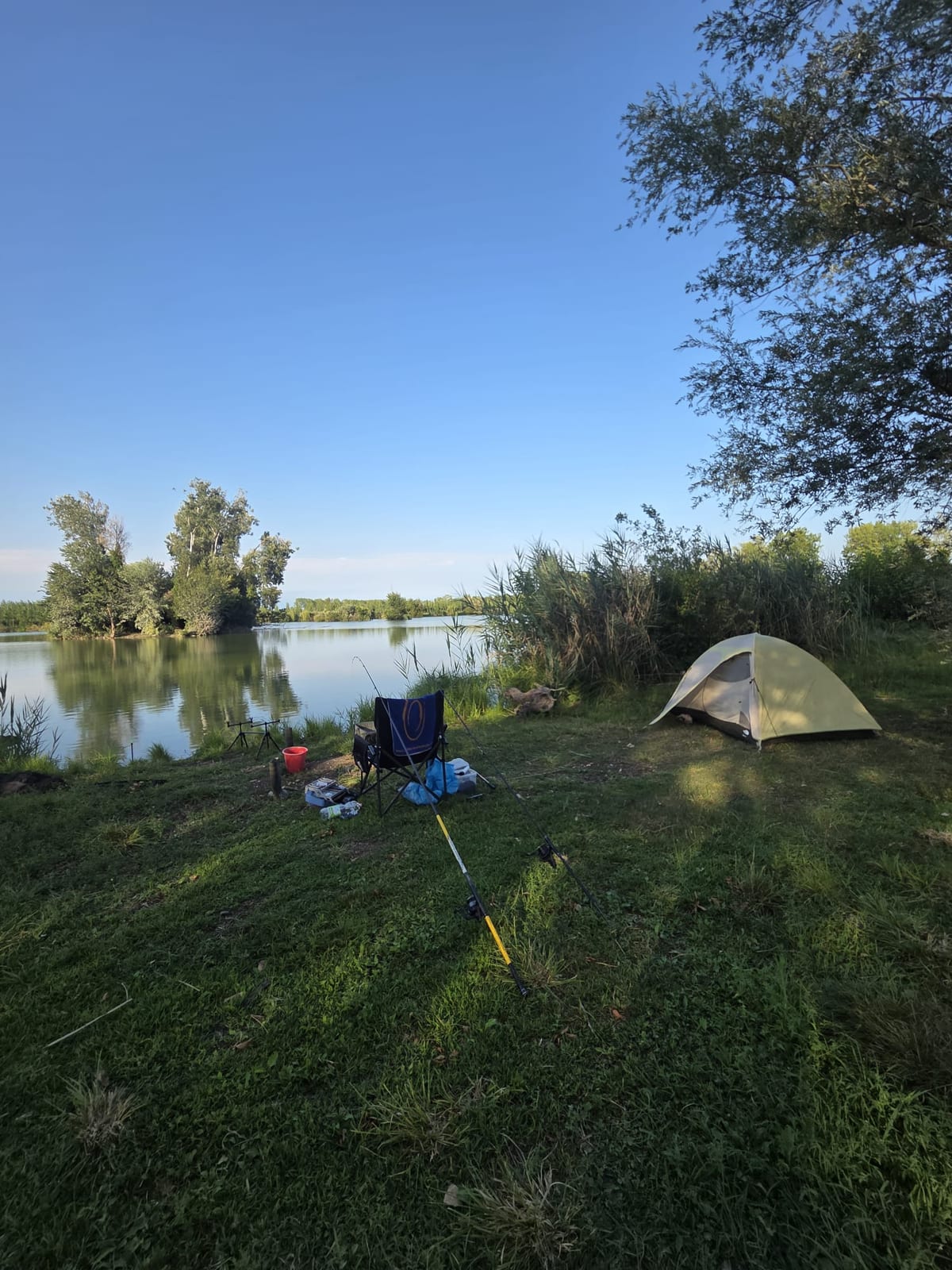 Il campo montato, tenda e canne davanti al lago
